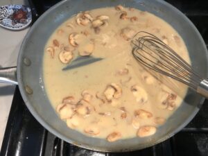 Thickened mushroom sauce in skillet for Chicken Stroganoff with mushrooms, and spinach. It has a thick, creamy, savory mushroom sauce with a touch of tangy sour cream. #chickendinners #chickenrecipes #familydinners #dinnerideas