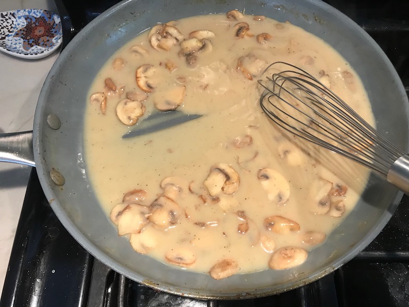 Thickened mushroom sauce in skillet for Chicken Stroganoff with mushrooms, and spinach. It has a thick, creamy, savory mushroom sauce with a touch of tangy sour cream. #chickendinners #chickenrecipes #familydinners #dinnerideas