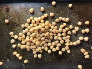 Chickpeas on pan for Mediterranean SHEET PAN DINNER with chicken sausage, parmesan zucchini. and crispy chickpeas. Serve over quinoa with dollops of seasoned Ricotta. #sheetpandinner #chickpeas