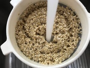 Rinsing quinoa in strainer for Mediterranean SHEET PAN DINNER with chicken sausage, parmesan zucchini. and crispy chickpeas. Serve over quinoa with dollops of seasoned Ricotta. #sheetpandinner #chickpeas