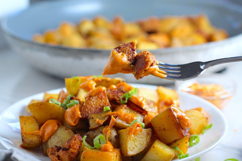 Patatas Bravas with chorizo on a plate with chorizo and creamy Paprika aioli drizzled over top. This Patatas Bravas Recipe, or Spicy Potatoes, is easy, indulgent, and utterly delicious!
