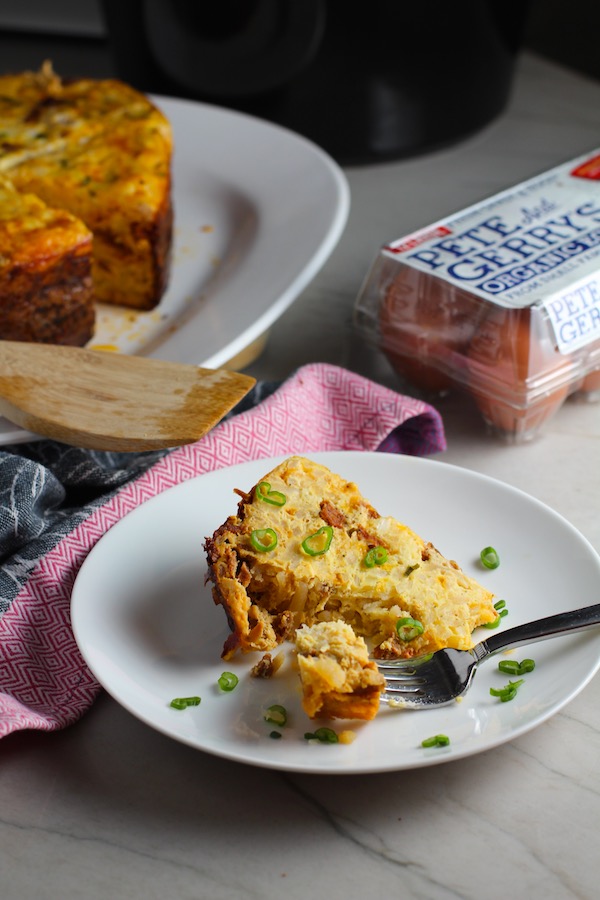 Piece of Slow Cooker Egg Casserole on a plate with Pete & Gerry's Eggs in background. It has Chorizo, Potatoes and both cheddar and manchego cheeses. IT COOKS WHILE YOU SLEEP! #eggs #eggcasseroles #eggrecipes #breakfastideas #holidayrecipes