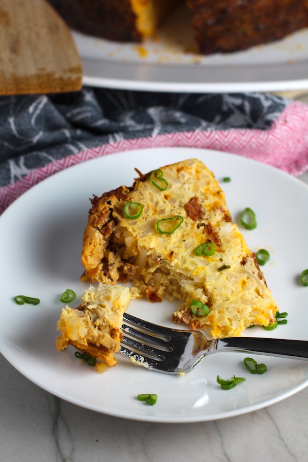Piece of Slow Cooker Egg Casserole on a plate with scallions. It has Chorizo, Potatoes and both cheddar and manchego cheeses. IT COOKS WHILE YOU SLEEP! #eggs #eggcasseroles #eggrecipes #breakfastideas #holidayrecipes