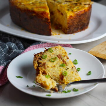Piece of Slow Cooker Egg Casserole on a plate with scallions. It has Chorizo, Potatoes and both cheddar and manchego cheeses. IT COOKS WHILE YOU SLEEP! #eggs #eggcasseroles #eggrecipes #breakfastideas #holidayrecipes