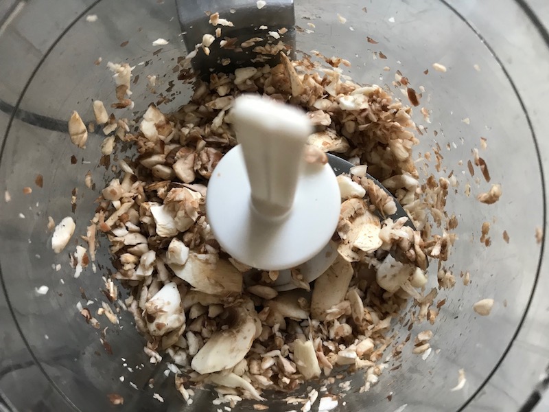 Mushrooms in food processor for Mini Beef Wellington Bites. They are flaky and buttery Puff Pastry is filled with a creamy mushroom and parmesan filling and tender beef filet. #appetizers #partyfood