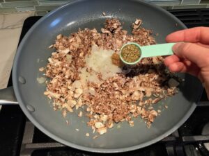 Mushrooms, onions, seasoning in pan for Mini Beef Wellington Bites. They are flaky and buttery Puff Pastry is filled with a creamy mushroom and parmesan filling and tender beef filet. #appetizers #partyfood