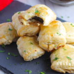 Mini Beef Wellington Bites stacked on platter. They are flaky and buttery on the outside. Puff Pastry is filled with a creamy mushroom and parmesan filling and tender beef filet.  #appetizers #partyfood
