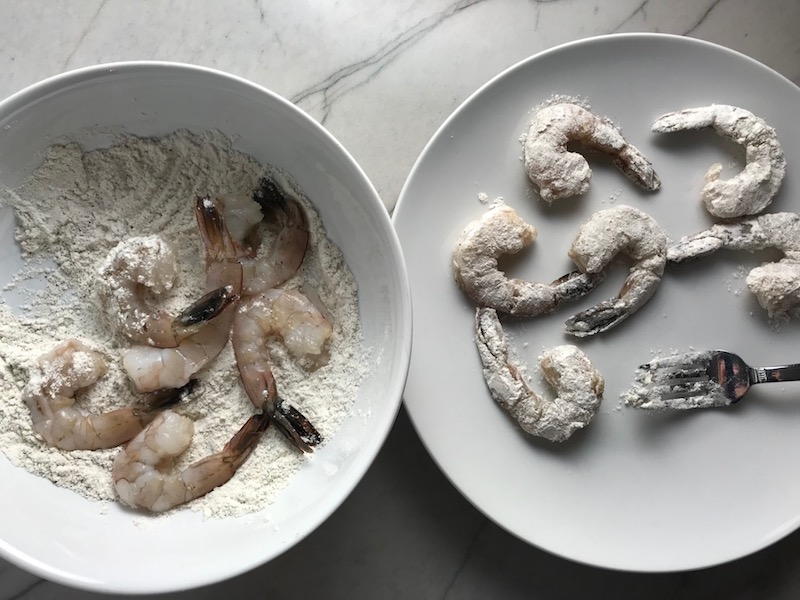 Raw shrimp in flour in a bowl for the Orange Brown Butter Shrimp Pasta Recipe. It has a silky sauce that's buttery, nutty, and slightly sweet! #shrimprecipes #shrimppasta #easydinners #dinnerideas