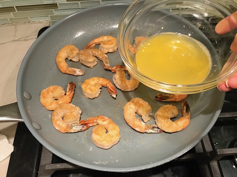 Adding orange juice to shrimp in skillet for the Orange Brown Butter Shrimp Pasta Recipe. #shrimprecipes #shrimppasta #easydinners #dinnerideas