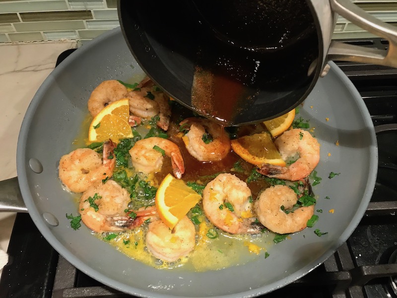 Adding brown butter to shrimp in skillet for the Orange Brown Butter Shrimp Pasta Recipe. #shrimprecipes #shrimppasta #easydinners #dinnerideas