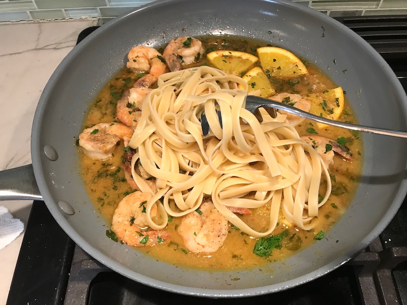 Pasta added to Shrimp and orange sauce in skillet for the Orange Brown Butter Shrimp Pasta Recipe. #shrimprecipes #shrimppasta #easydinners #dinnerideas