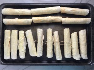 Chicken Taquitos on pan before baking. Corn tortillas are filled with smoky taco seasoned shredded chicken, and creamy cheddar cheese. #dinnerideas #familydinner #chickenrecipes #chickendinner #tacos #taquitos
