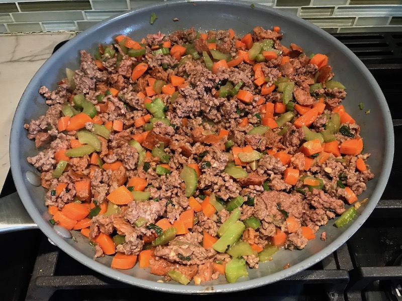 Beef filling in pan for Cottage Pie recipe. It has Spanish Chorizo and ground beef cooked in a rich and savory gravy with veggies and herbs. Creamy mashed potatoes sit on top with manchego, parmesan, and garlic. #dinnerideas #cottagepie #shepherdspie
