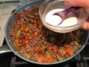 Beef filling in pan for Cottage Pie recipe. It has Spanish Chorizo and ground beef cooked in a rich and savory gravy with veggies and herbs. Creamy mashed potatoes sit on top with manchego, parmesan, and garlic. #dinnerideas #cottagepie #shepherdspie