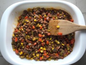 Beef filling in pan for Cottage Pie recipe. It has Spanish Chorizo and ground beef cooked in a rich and savory gravy with veggies and herbs. Creamy mashed potatoes sit on top with manchego, parmesan, and garlic. #dinnerideas #cottagepie #shepherdspie