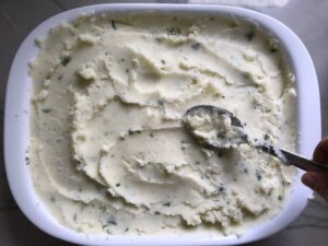 Covering filling with potatoes for Cottage Pie recipe. It has Spanish Chorizo and ground beef cooked in a rich and savory gravy with veggies and herbs. Creamy mashed potatoes sit on top with manchego, parmesan, and garlic. #dinnerideas #cottagepie #shepherdspie