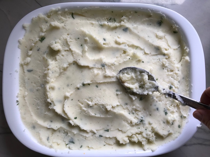 Covering filling with potatoes for Cottage Pie recipe. It has Spanish Chorizo and ground beef cooked in a rich and savory gravy with veggies and herbs. Creamy mashed potatoes sit on top with manchego, parmesan, and garlic. #dinnerideas #cottagepie #shepherdspie