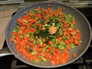 Veggies in skillet cooking for Cottage Pie recipe. It has Spanish Chorizo and ground beef cooked in a rich and savory gravy with veggies and herbs. Creamy mashed potatoes sit on top with manchego, parmesan, and garlic. #dinnerideas #cottagepie #shepherdspie