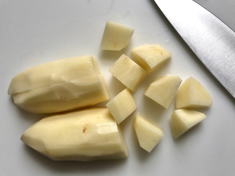 Cutting raw potatoes for Cottage Pie recipe. It has Spanish Chorizo and ground beef cooked in a rich and savory gravy with veggies and herbs. Creamy mashed potatoes sit on top with manchego, parmesan, and garlic. #dinnerideas #cottagepie #shepherdspie