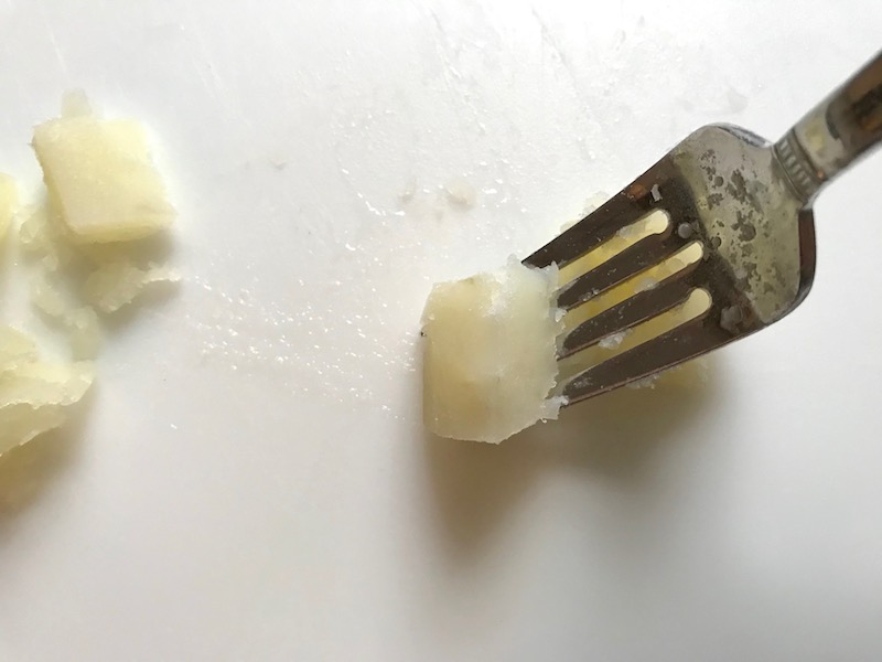 Fork in cooked potato for Cottage Pie recipe. It has Spanish Chorizo and ground beef cooked in a rich and savory gravy with veggies and herbs. Creamy mashed potatoes sit on top with manchego, parmesan, and garlic. #dinnerideas #cottagepie #shepherdspie