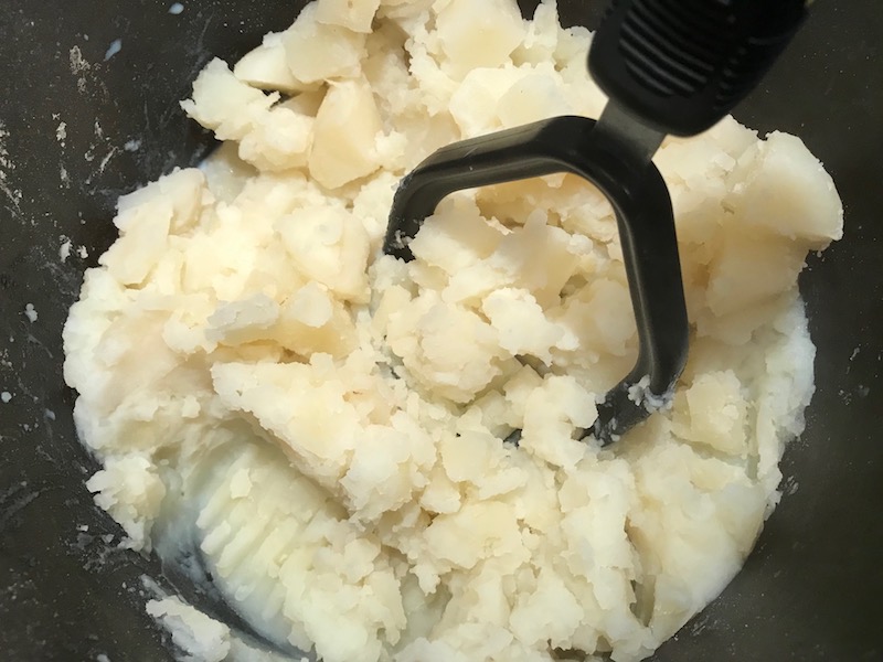 Mashing potatoes for Cottage Pie recipe. It has Spanish Chorizo and ground beef cooked in a rich and savory gravy with veggies and herbs. Creamy mashed potatoes sit on top with manchego, parmesan, and garlic. #dinnerideas #cottagepie #shepherdspie
