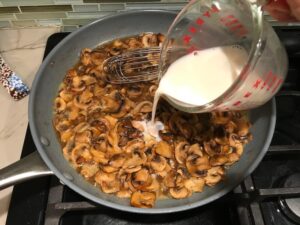 Adding slurry to cooked sliced Mushrooms in skillet for this Heavenly Mushroom Sauce Recipe. #vegetarian #healthydinner #dinnerideas #mushrooms