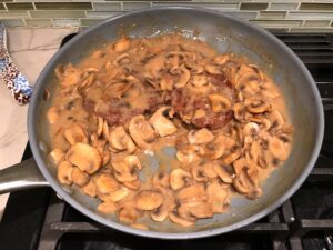 Beyond burgers in mushroom sauce in skillet for Vegetarian Salisbury Steak with a thick, creamy, rich Mushroom Sauce. #vegetarian #healthydinner #dinnerideas #mushrooms