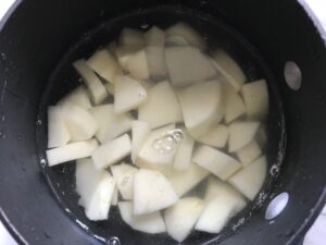 Cut raw potatoes in pot for Cauliflower Gnocchi, which are soft, silky, buttery, and melt-in-your-mouth! Made with cauliflower, they're a healthier version to traditional gnocchi! Add my simple Garlic Butter Sauce or Tomato Sauce and they are heaven.  #dinnerideas #gnocchi #cauliflower