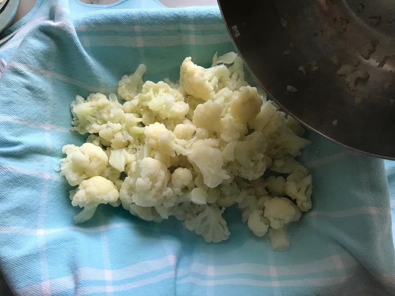 Cooked cauliflower in dish towel for Cauliflower Gnocchi, which are soft, silky, buttery, and melt-in-your-mouth! Made with cauliflower, they're a healthier version to traditional gnocchi! Add my simple Garlic Butter Sauce or Tomato Sauce and they are heaven. #dinnerideas #gnocchi #cauliflower