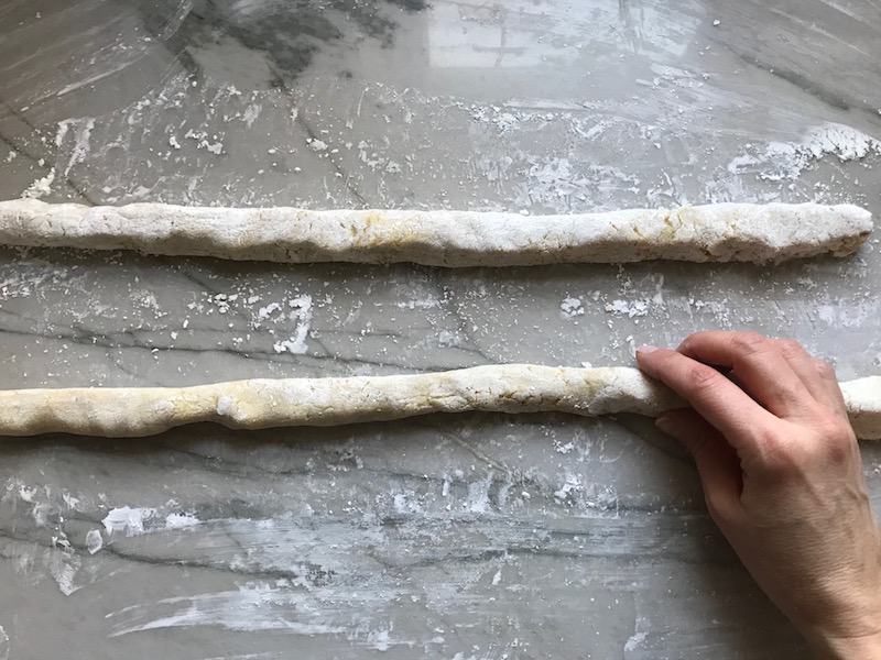 Rolling out gnocchi dough into ropes on surface for cauliflower gnocchi dough. These Gnocchi are soft, silky, buttery, and melt-in-your-mouth! Made with cauliflower, they're a healthier version to traditional gnocchi! Add my simple Garlic Butter Sauce or Tomato Sauce and they are heaven. #dinnerideas #gnocchi #cauliflower