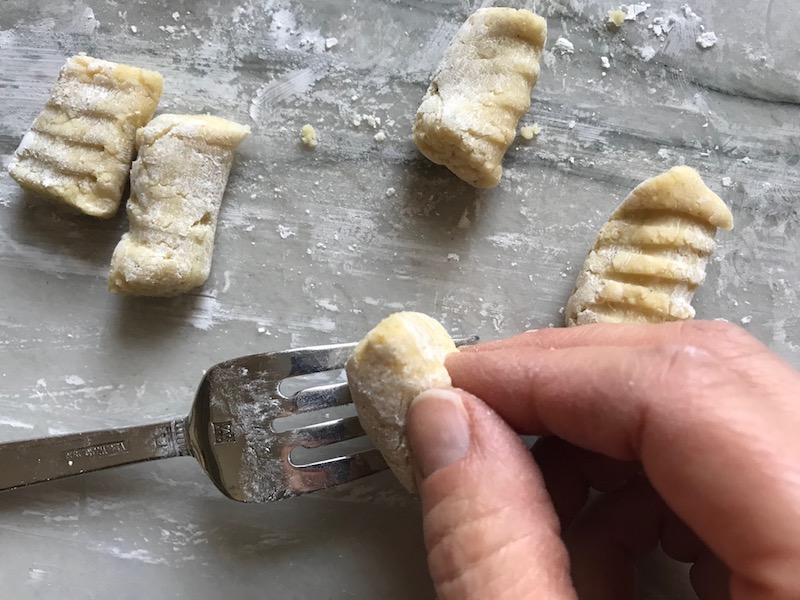 Rolling gnocchi on fork on for cauliflower gnocchi. These Gnocchi are soft, silky, buttery, and melt-in-your-mouth! Made with cauliflower, they're a healthier version to traditional gnocchi! Add my simple Garlic Butter Sauce or Tomato Sauce and they are heaven. #dinnerideas #gnocchi #cauliflower