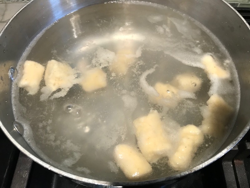 Cauliflower gnocchi cooking in boiling water. These Gnocchi are soft, silky, buttery, and melt-in-your-mouth! Made with cauliflower, they're a healthier version to traditional gnocchi! Add my simple Garlic Butter Sauce or Tomato Sauce and they are heaven. #dinnerideas #gnocchi #cauliflower