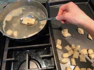 Transfering cooked cauliflower gnocchi from water to sheet pan. These Gnocchi are soft, silky, buttery, and melt-in-your-mouth! Made with cauliflower, they're a healthier version to traditional gnocchi! Add my simple Garlic Butter Sauce or Tomato Sauce and they are heaven.  #dinnerideas #gnocchi #cauliflower