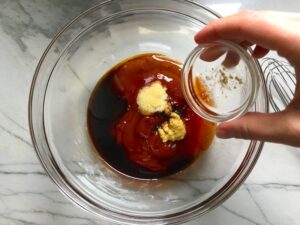Hand adding ingredients to bowl for Chinese BBQ Sauce for Pork Tenderloin. It's sweet, tangy, salty, and all together lick-your-fingers delicious! It's also easy to make! #chinesebbqsauce #bbq #bbqsauce