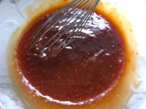 Hand adding ingredients to bowl for Chinese BBQ Sauce for Pork Tenderloin. It's sweet, tangy, salty, and all together lick-your-fingers delicious! It's also easy to make! #chinesebbqsauce #bbq #bbqsauce