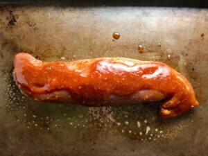 Raw Pork Tenderloin with sauce on pan for Chinese BBQ Sauce for Pork Tenderloin. It's sweet, tangy, salty, and all together lick-your-fingers delicious! It's also easy to make! #chinesebbqsauce #bbq #bbqsauce