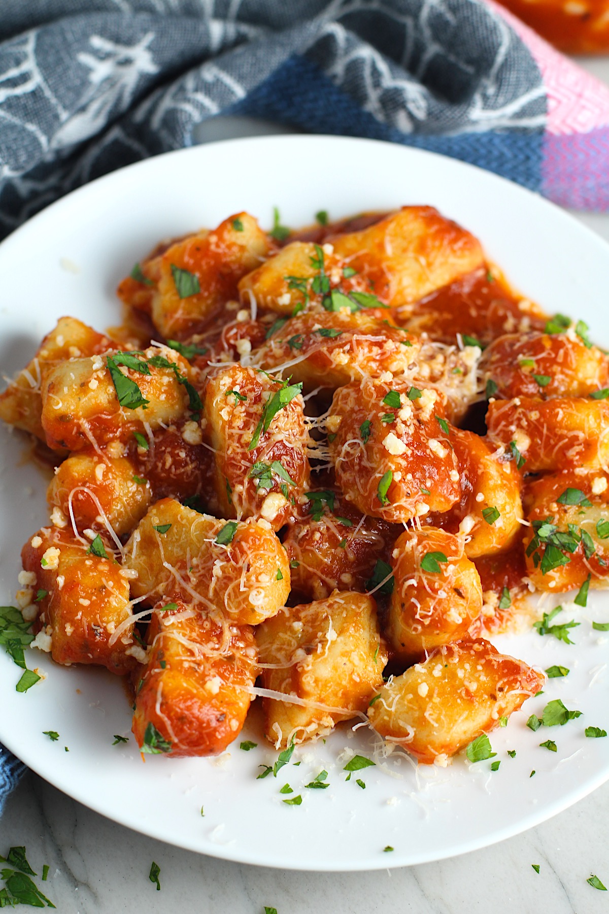 Cauliflower Gluten Free Gnocchi recipe in tomato sauce on plate with parmesan and parsley.