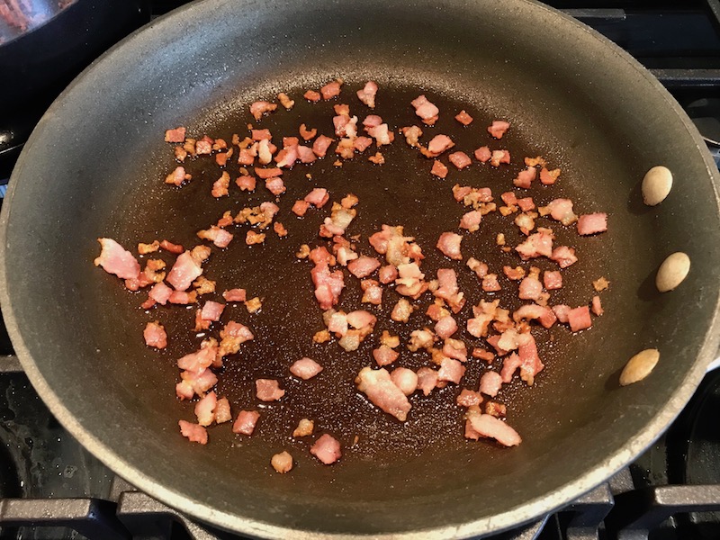 Cooked bacon pieces in pan for Bacon Mac and Cheese. It has a creamy and cheesy sauce with a touch of smokiness from the bacon, coats each piece of pasta. On top, crispy crunchy, indulgent bacon fat cracker crumbs!