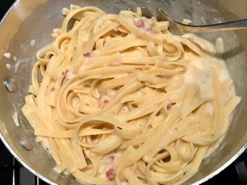 Mixing fettuccine into cheese sauce for Bacon Mac and Cheese. It has a creamy and cheesy sauce with a touch of smokiness from the bacon, coats each piece of pasta. On top, crispy crunchy, indulgent bacon fat cracker crumbs!