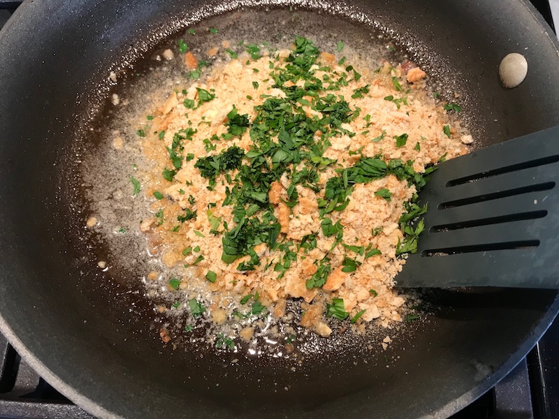 Cracker crumbs and parsley in pan for Bacon Mac and Cheese. It has a creamy and cheesy sauce with a touch of smokiness from the bacon, coats each piece of pasta. On top, crispy crunchy, indulgent bacon fat cracker crumbs!