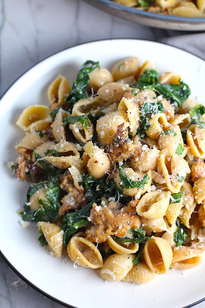 Italian Chicken Sausage Pasta with Kale on a plate. It's loaded with a salty homemade Chicken Italian Sausage flavored with garlic and fennel in a parmesan, garlic and kale sauce. 