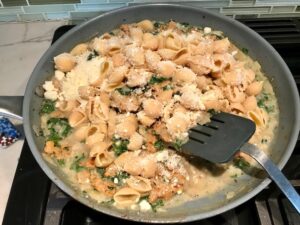 Mixing parmesan with pasta and Italian Sausage in pan for Shell Pasta with Italian Sausage and Kale. It's loaded with a salty homemade Chicken Italian Sausage flavored with garlic and fennel in a parmesan, garlic and kale sauce.