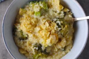 Broccoli Cheese Quinoa Bake in a bowl with potato chips on top. It's a comfy cozy casserole that's perfect to make ahead for a simple weeknight side or main dish.