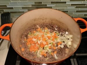 Veggies and beef in pot for Chili Mac and Cheese. This Recipe has creamy and cheesy pasta topped with smokey, tangy, savory beef chili! #macandcheese #chilirecipes