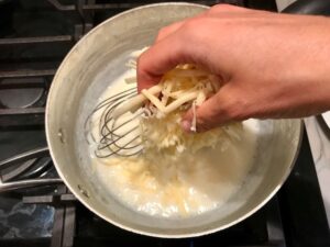 Adding cheese to sauce for Chili Mac and Cheese. This Recipe has creamy and cheesy pasta topped with smokey, tangy, savory beef chili! #macandcheese #chilirecipes