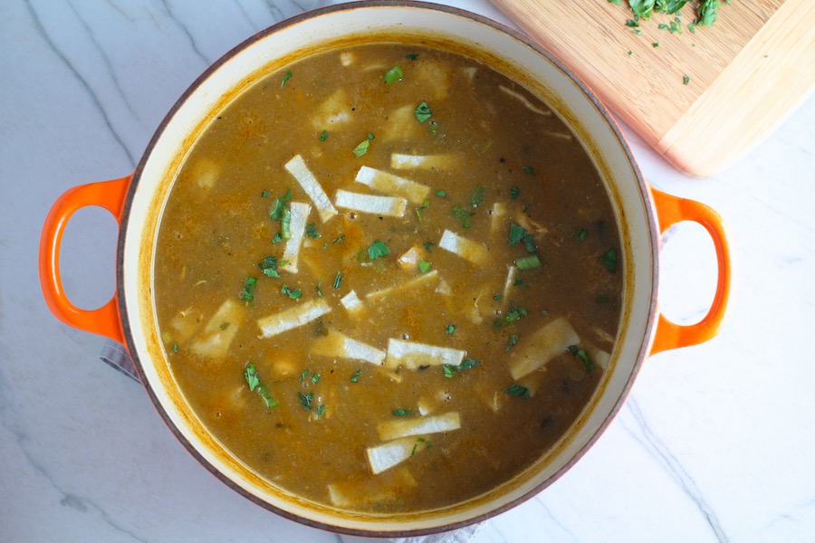 Creamy Chicken Enchilada Soup in a pot. It's creamy, hearty, slightly spicy with green chiles and smokey seasonings that bring so much depth. Corn tortilla strips act like the noodles in this soup!