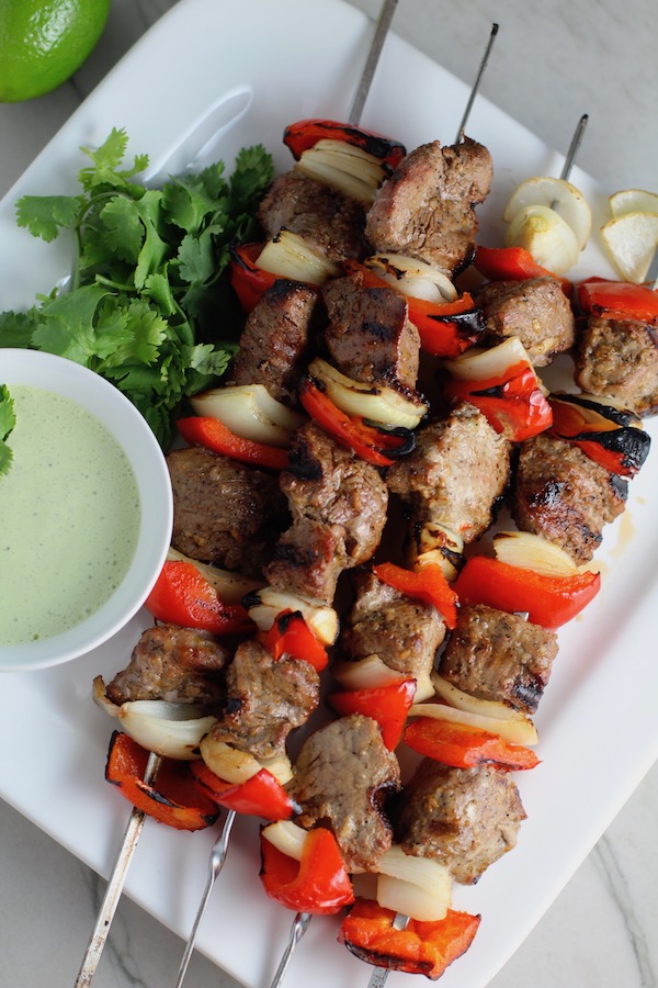 Garlic Steak Kabobs with red pepper and onion on platter with a Creamy Cilantro Sauce! #beefkabobs #steakkabobs