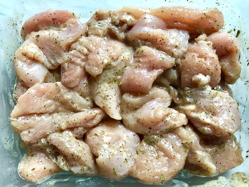 Chicken in marinade in bowl for Tarragon Mustard Chicken with Red Peppers. It's creamy, tangy, savory, and so addictive.