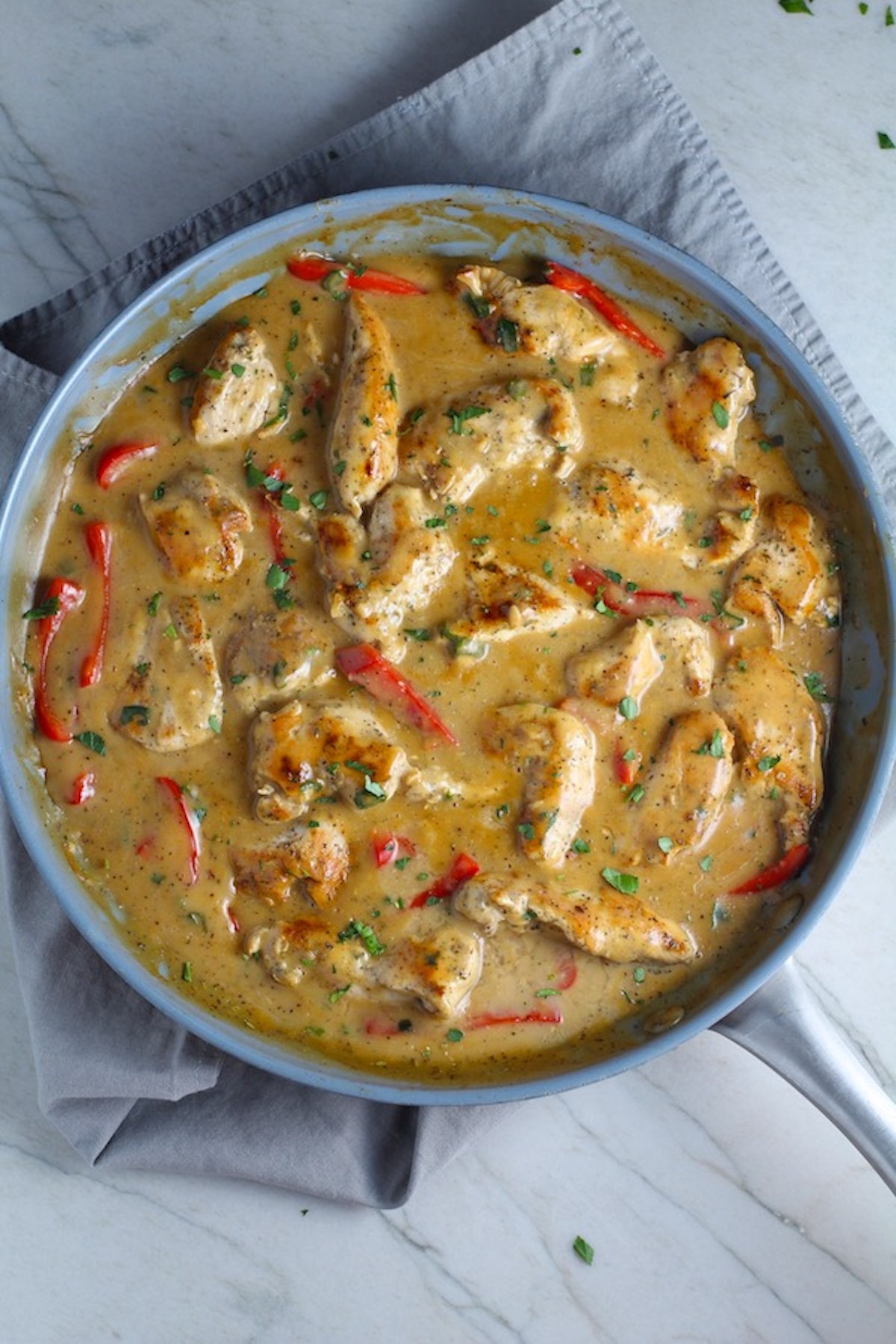 Tarragon Mustard Sauce for Chicken Without Cream with red peppers in a pan on towel on counter. It gets so much flavor from dijon mustard, tarragon, garlic, and onion. It's an easy-to-whip-up any night dinner!