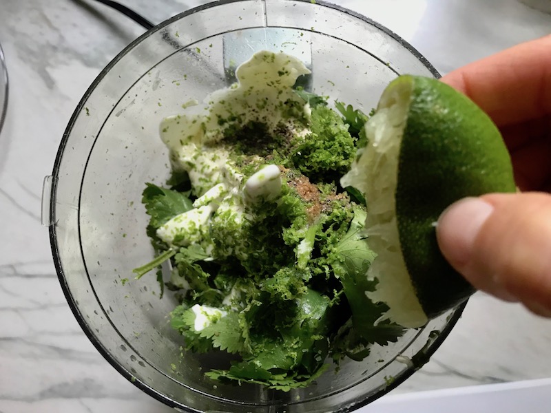 Squeezing lime into cilantro sauce ingredients in food processor for Garlic Steak Kabobs. #beefkabobs #steakkabobs